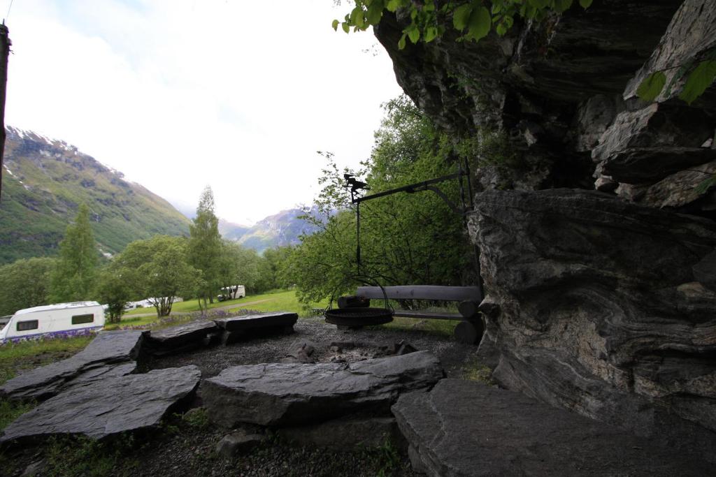 a stone wall with a picnic table in a field at Vinje Camping in Geiranger