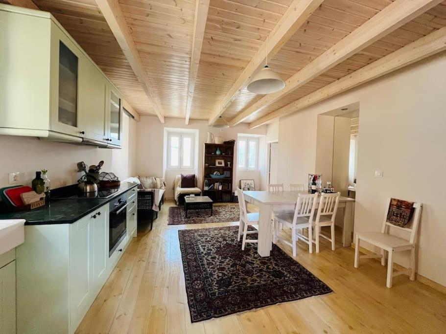 Il comprend une cuisine et un salon avec une table et des chaises. dans l'établissement Traditional Detached Corfu House, 50m to village square, à Liapades