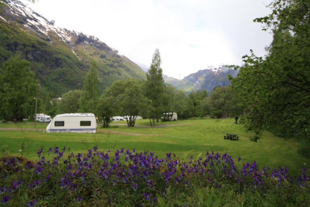 a white tent in a field with trees and mountains at Vinje Camping in Geiranger