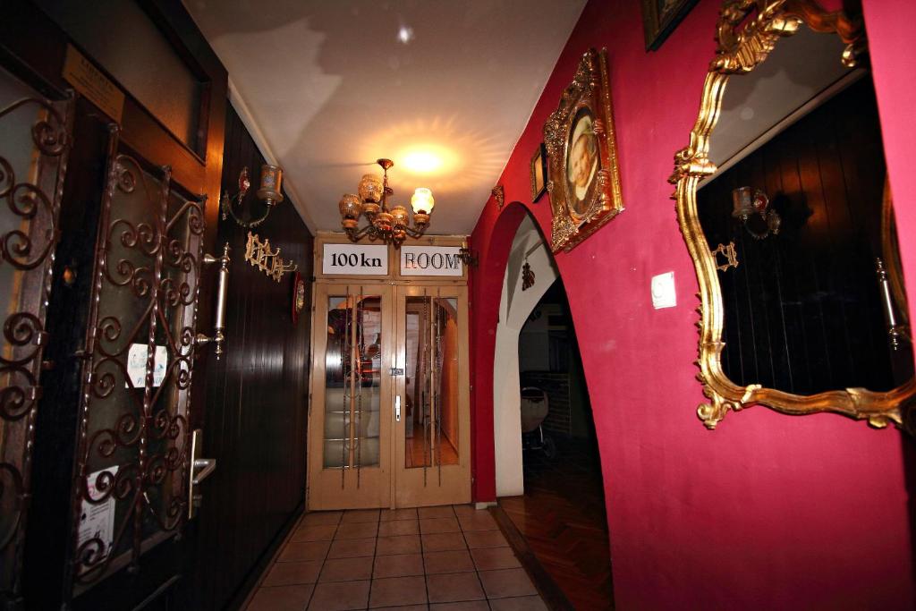 a hallway with a pink wall and a mirror at Rooms Ana in Osijek