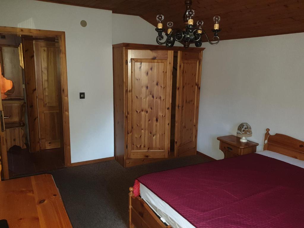 1 dormitorio con 1 cama y armario de madera en Appartamenti Nonno Gianni en Rocca Pietore