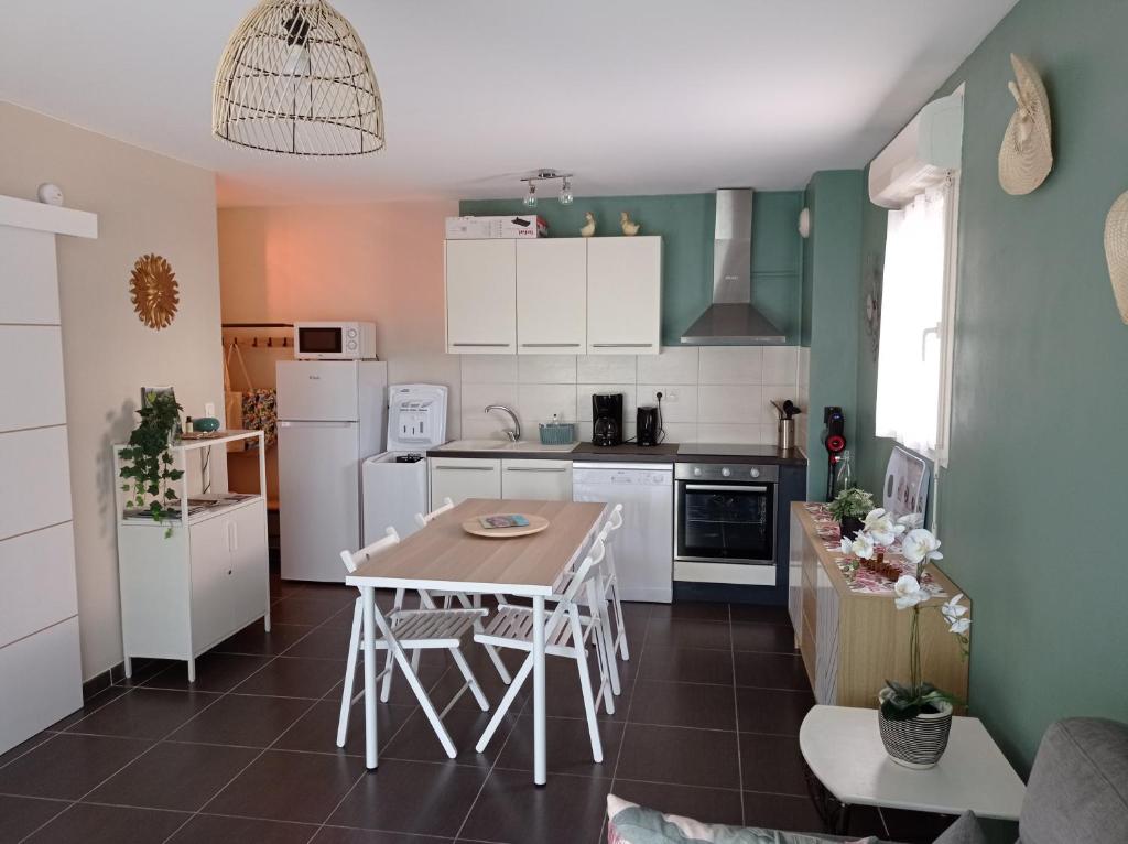 een keuken met witte apparatuur en een tafel bij LE SOLEIL DU LUBERON - T2 avec Terrasse, Parking et Clim in LʼIsle-sur-la-Sorgue