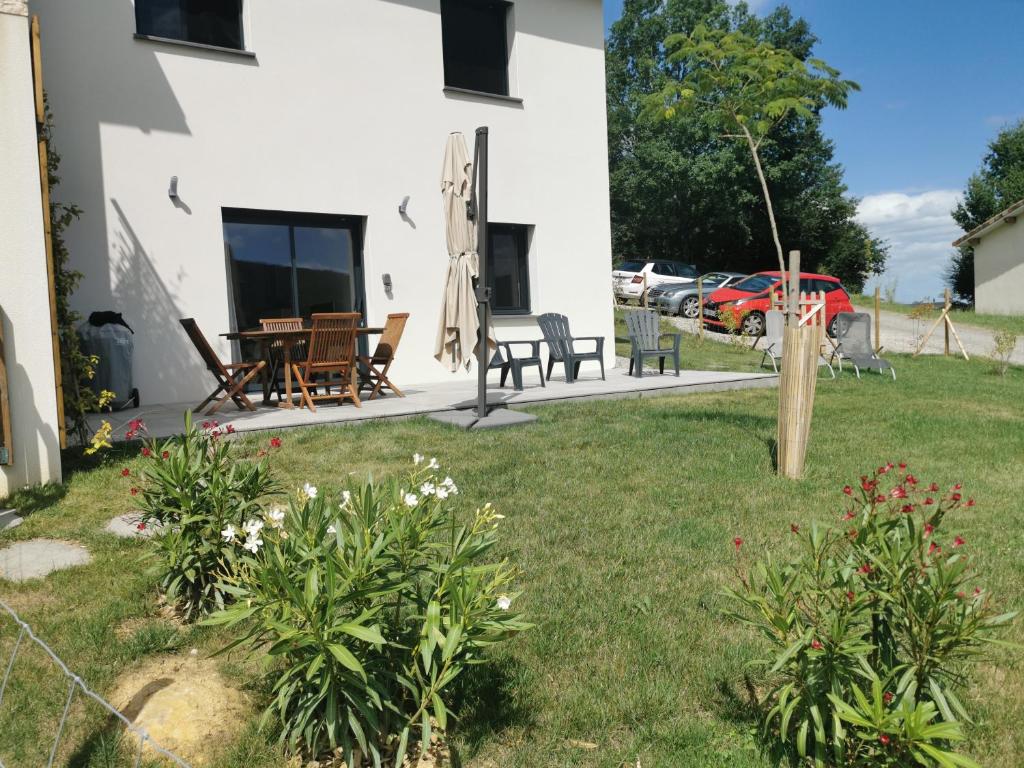 ein Haus mit einem Garten mit Stühlen und einem Tisch in der Unterkunft Gîte La Coumette - classé 3 étoiles in Crampagna