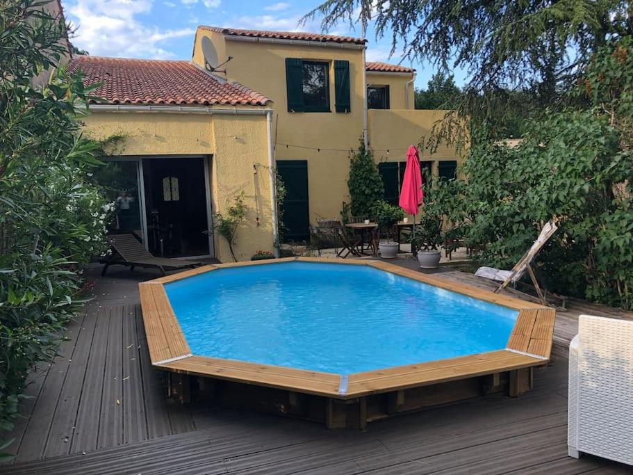 ein großer Pool auf einer Terrasse mit einem Haus in der Unterkunft Pavillon dans un écrin de verdure avec piscine in Lodève