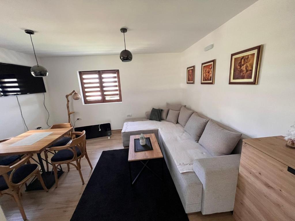 ein Wohnzimmer mit einem weißen Sofa und einem Tisch in der Unterkunft Zlatna Jabuka apartman in Prijepolje