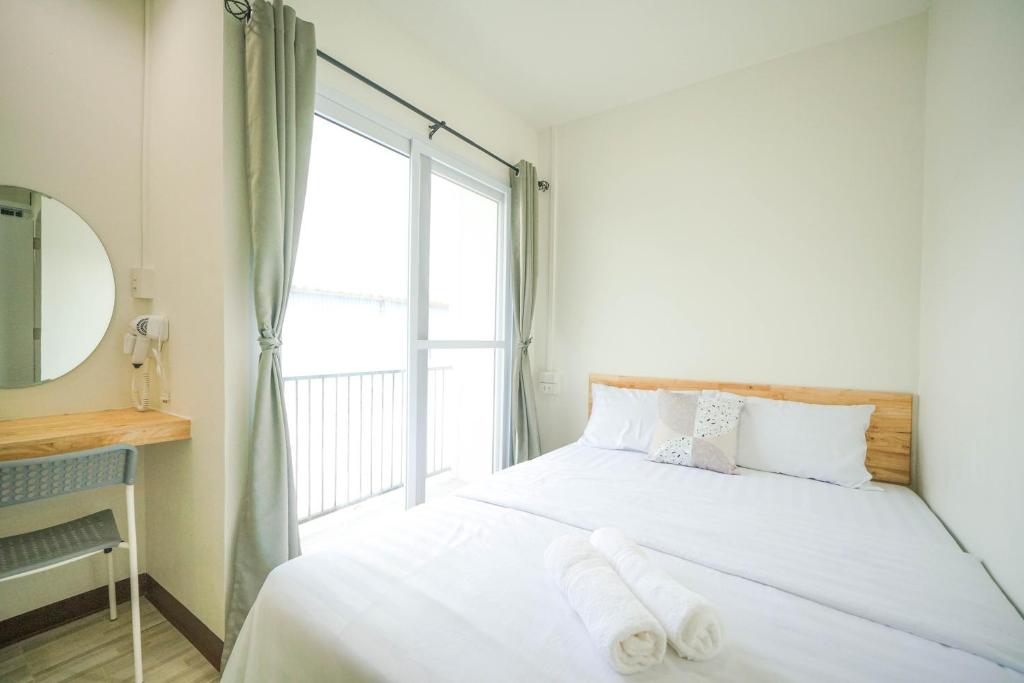 a bedroom with a bed with white sheets and a window at Nut Home Hostel in Ban Ko