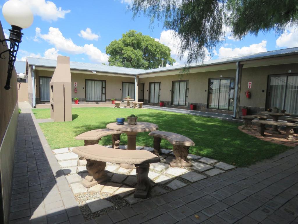 a patio with a table and benches in a yard at Andante Guesthouse Klerksdorp in Klerksdorp