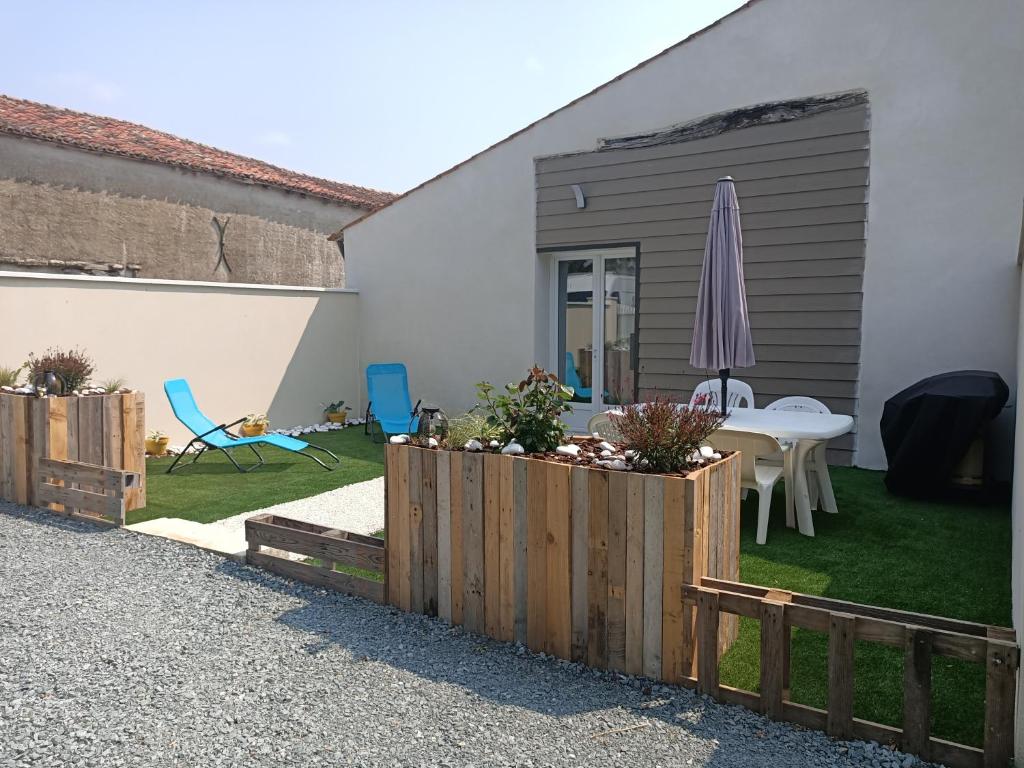 un patio trasero con una mesa y una sombrilla en Le hangar de mamie, en La Charrière