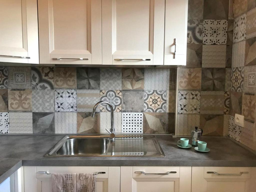 a kitchen with white cabinets and a sink at Trilocale in residence Verdesirente in Rocca di Mezzo