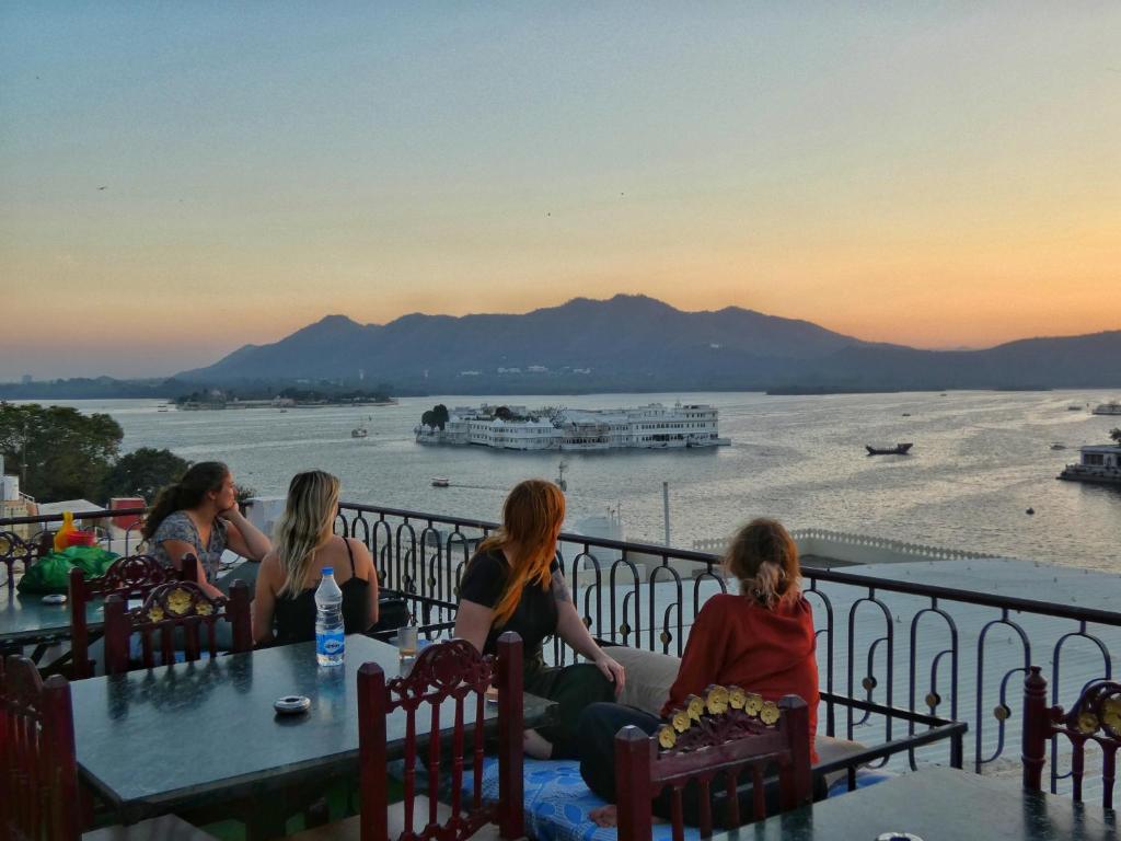 un grupo de mujeres sentadas en una mesa con vistas al agua en Dreamyard Udaipur, en Udaipur