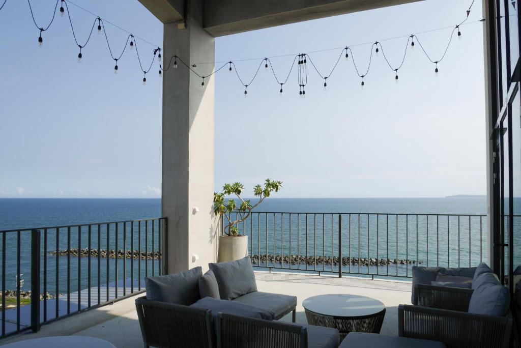 eine Terrasse mit Stühlen und Tischen und Meerblick in der Unterkunft 緩慢大鵬灣 in Donggang