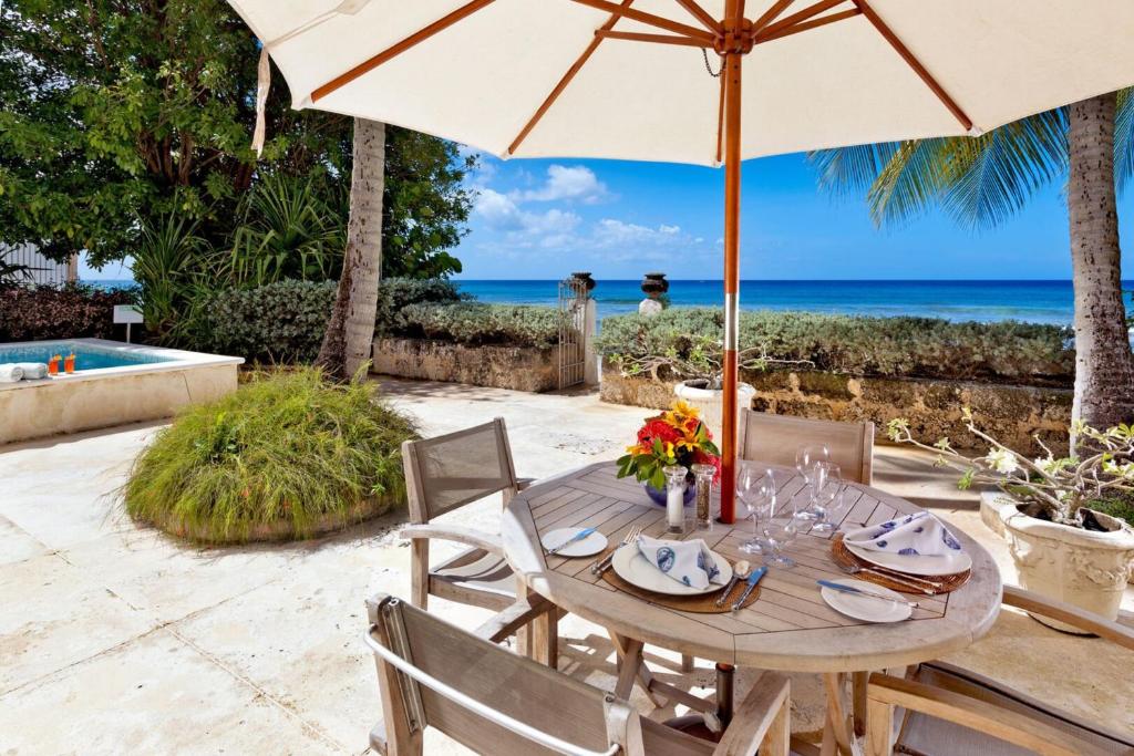 a table with an umbrella and the ocean in the background at Leamington Cottage in Saint Peter