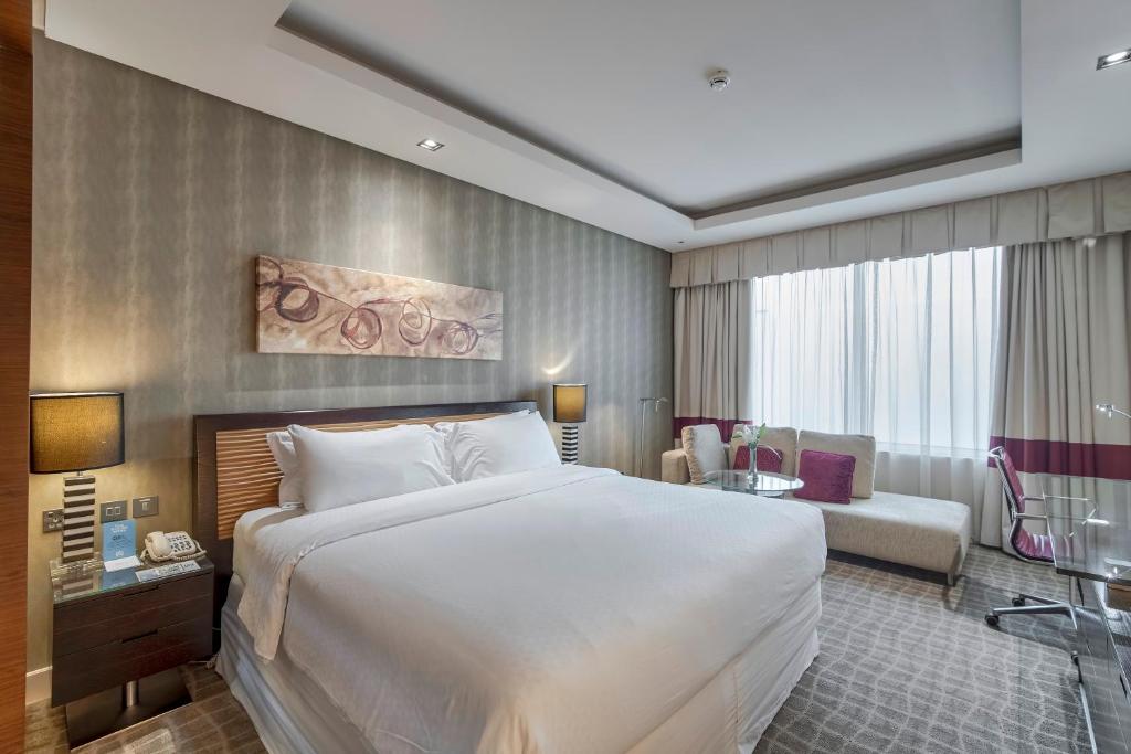 a hotel room with a large bed and a chair at Majestic Premier Hotel Burdubai in Dubai