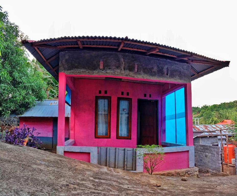 een klein rood huis met blauwe ramen op een heuvel bij Homestay Marly in Rinondoran