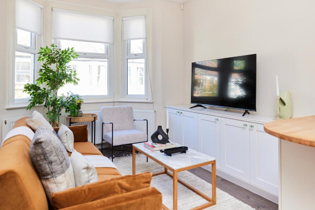 uma sala de estar com um sofá e uma televisão em The Kilburn Crib - Stunning 3BDR Flat em Londres