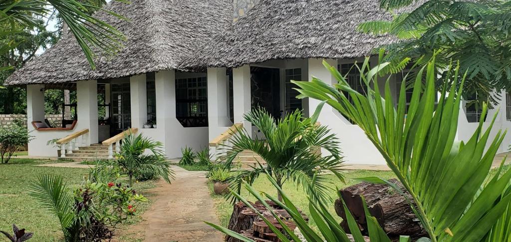 una casa con techo de paja y algunas plantas en Mangos Villas - Lucia en Kilifi