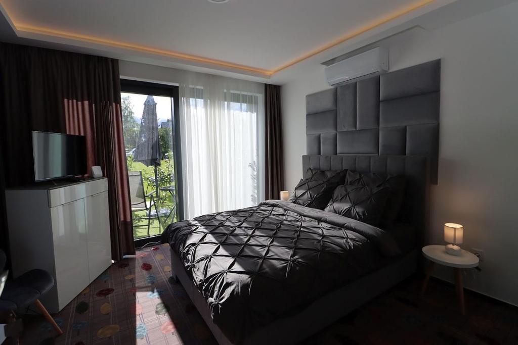 a bedroom with a black bed and a window at Prestige Miskolctapolca in Miskolc