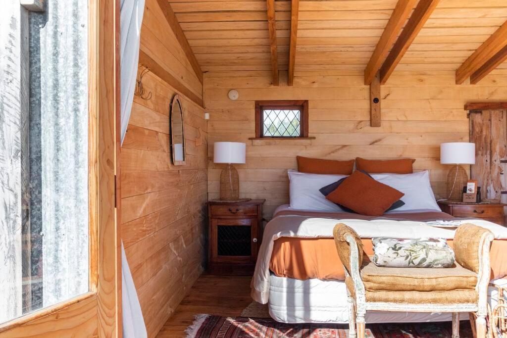 1 dormitorio con 1 cama en una cabaña de madera en FreeFall Hut, en Hastings