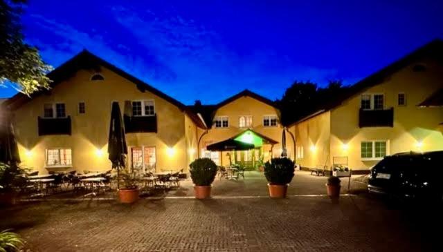 a couple of buildings with tables and chairs at night at Hotel Restaurant Ancho in Cölbe