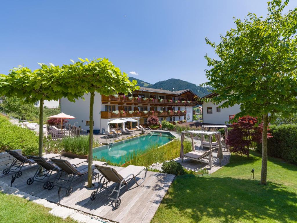 a resort with a pool and chairs and a building at Hotel Alpenpanorama in Söll