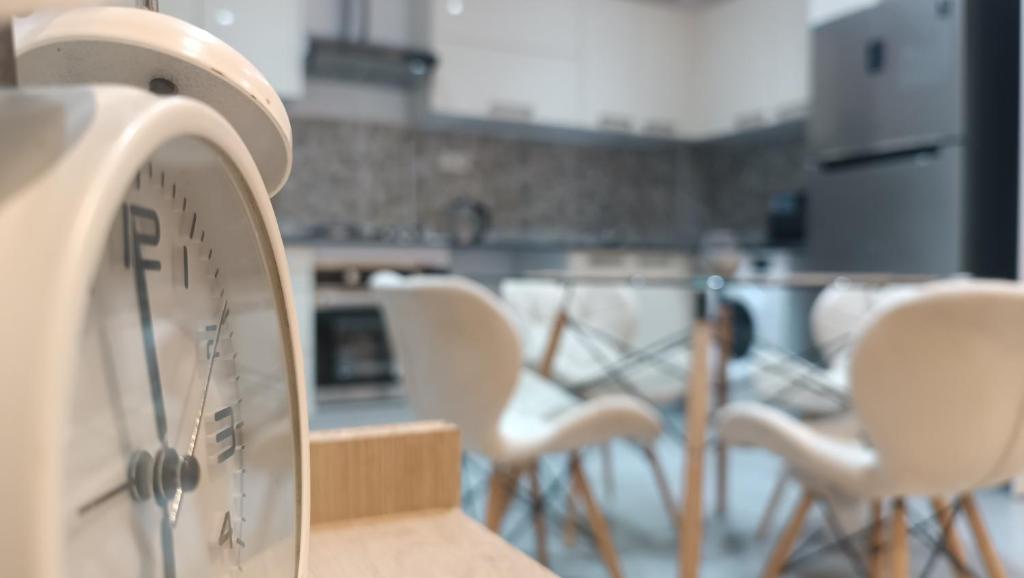 une horloge sur une table dans une pièce avec des chaises dans l'établissement Logement Chic, résidence azaléa - Alger, à Draria