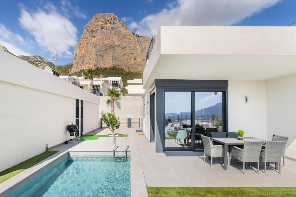 a house with a swimming pool and a table and chairs at Casa con piscina climatizada y vistas al mar in Polop