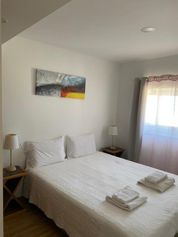 a bedroom with a white bed with two towels on it at Casa Berlengas a Vista in Peniche