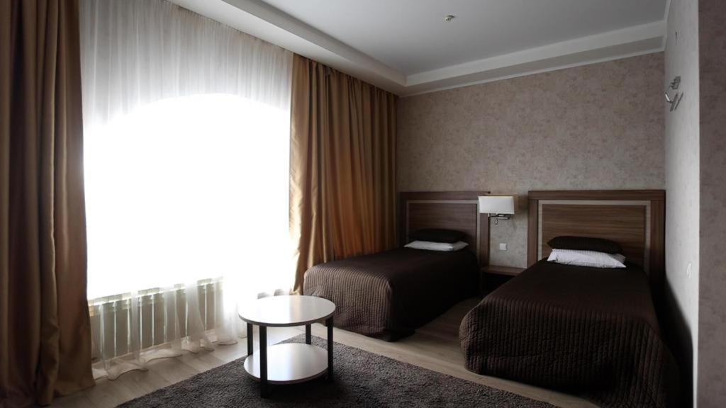 a hotel room with two beds and a window at Hotel Fessla in Kostanay