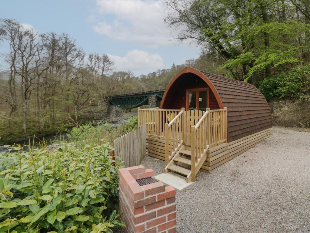 a small wooden cabin with a staircase in a garden at Pod No 28 in Keswick