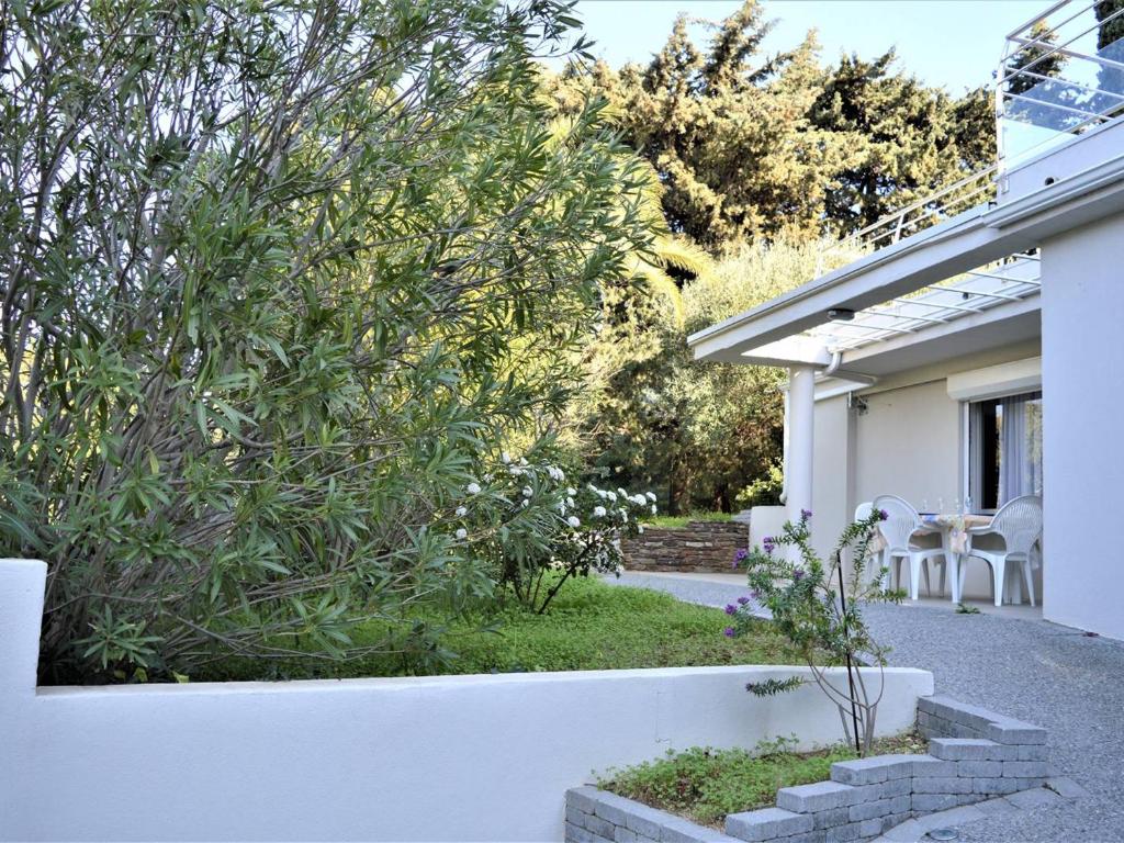 une maison blanche avec un jardin agrémenté d'une brousse dans l'établissement Calme Appartement T2 avec Terrasse à Cavalaire - FR-1-226B-2, à Cavalaire-sur-Mer