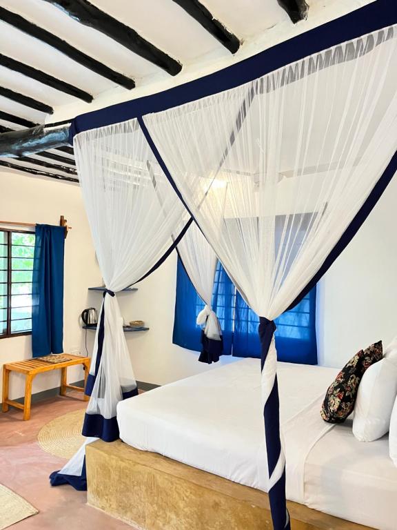 a bedroom with a bed with white curtains at Karanga Bungalows in Michamvi