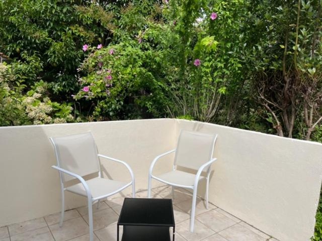 dos sillas blancas sentadas junto a una pared blanca en Maison - jardin aux portes de Bordeaux, en Cenon