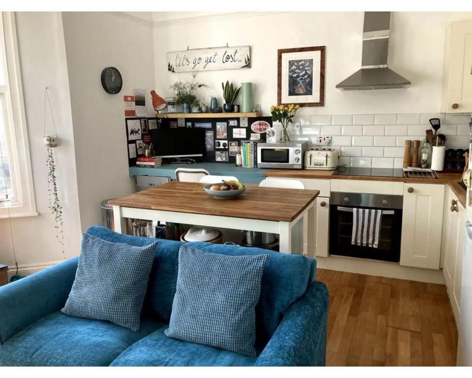 a living room with a blue couch and a kitchen at Bright, book-filled flat in artsy Stokes Croft in Bristol