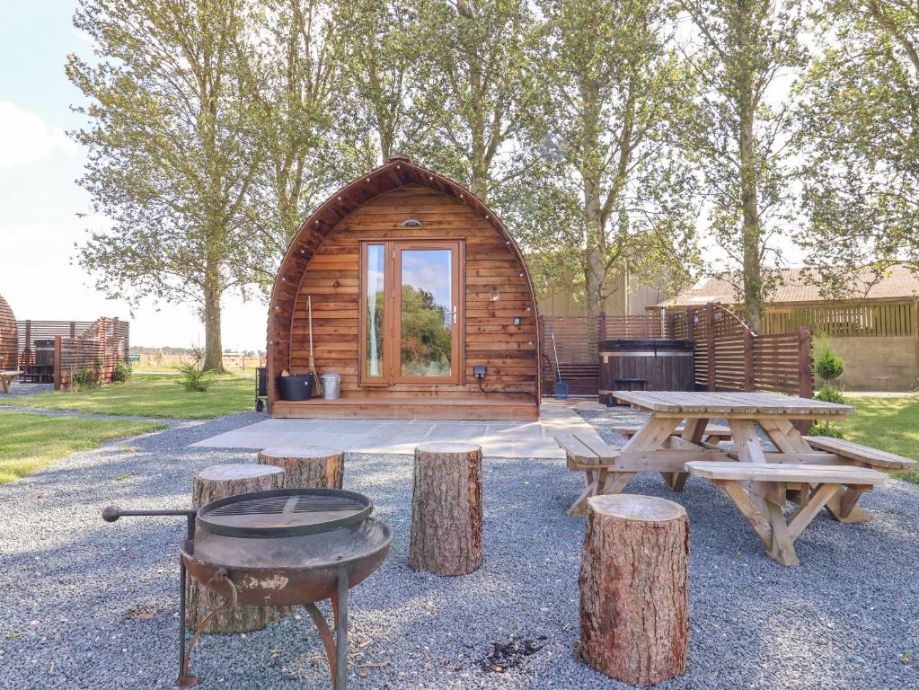 a log cabin with a grill and picnic tables at Mischief in Harpham