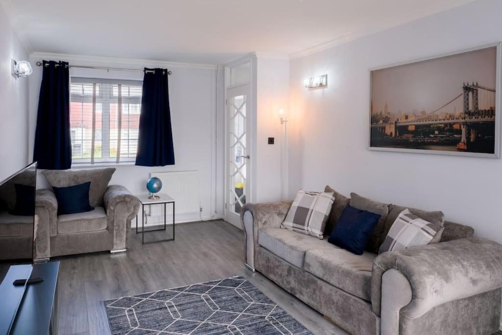 een woonkamer met twee banken en een schilderij aan de muur bij Cosy Luxurious 3-Bedroom Home in Birmingham
