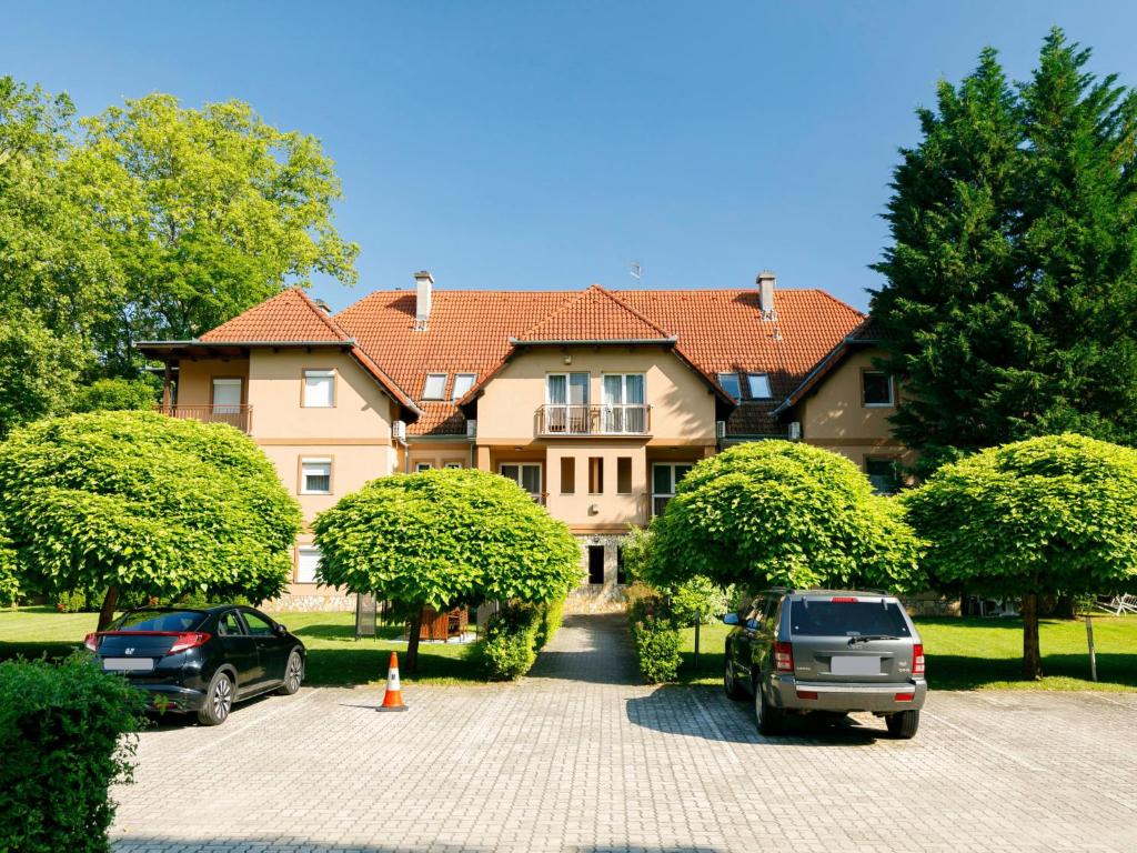 a large house with cars parked in a parking lot at Apartment Catalpa by Interhome in Balatonföldvár