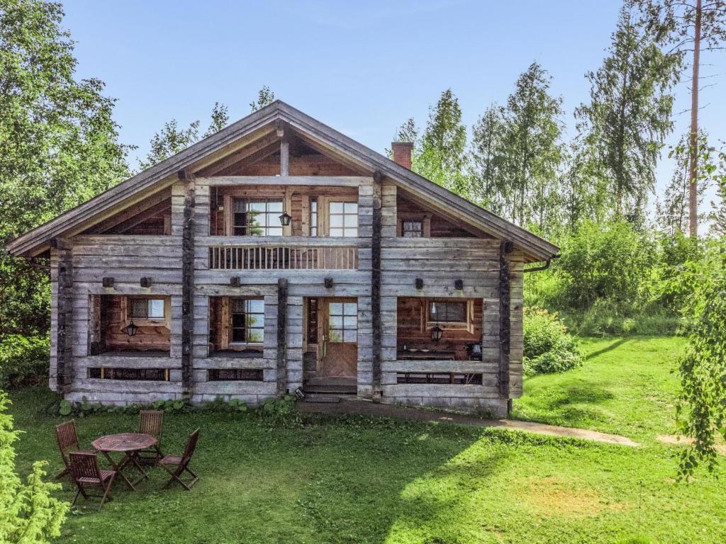 une maison en rondins avec une table et des chaises dans la cour dans l'établissement Holiday Home Karjalan kelohuvila by Interhome, à Muurasjärvi