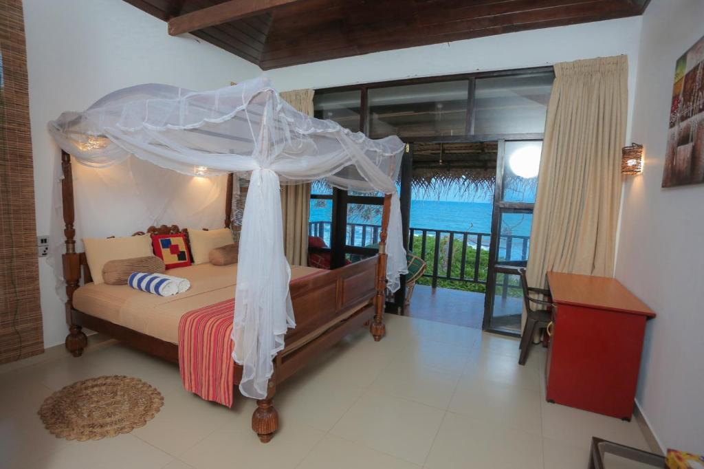 a bedroom with a canopy bed with a view of the ocean at Blue Ocean Resort in Netolpitiya