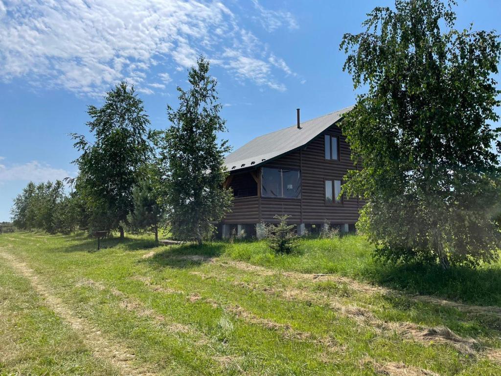 a wooden house in a field next to trees at AVALON - Котедж на озері in Borysxaw