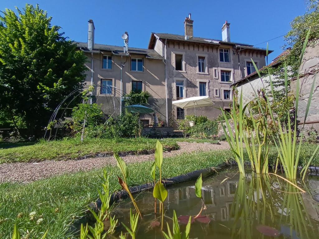une maison et un étang dans une cour dans l'établissement La petite chouette, à Rochesson