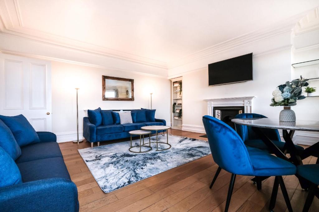 a living room with blue furniture and a table at Harrods Knightsbridge Flat in Central KB89 in London