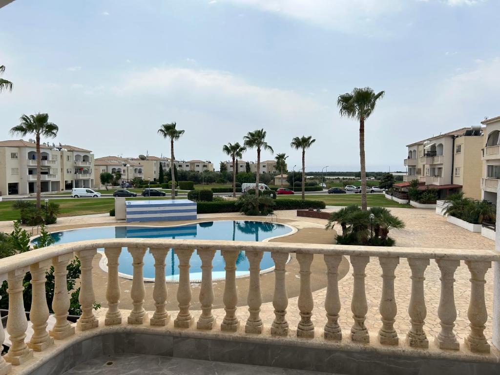 a balcony of a resort with a pool and palm trees at Holiday Mandria apt with pool in Paphos
