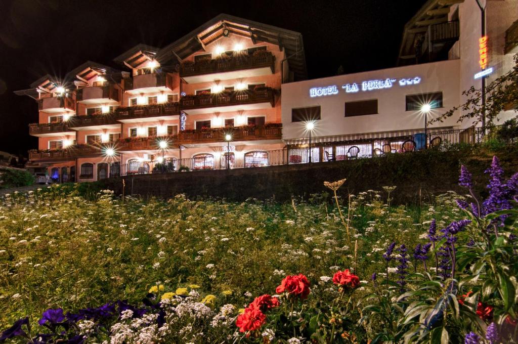 a building with a field of flowers in front of it at Family Hotel La Perla in Fiera di Primiero