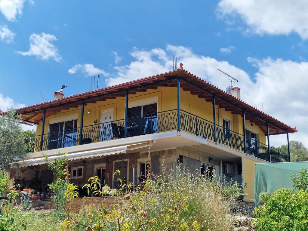 une maison jaune avec un balcon au-dessus dans l'établissement Grieks vakantiehuis To Kalokairi, à Kalamákion