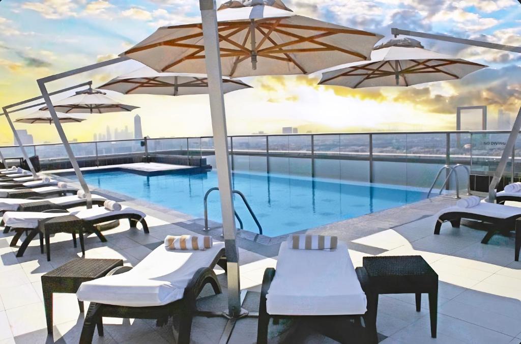 a swimming pool with tables and umbrellas on a building at Park Regis Kris Kin Hotel in Dubai