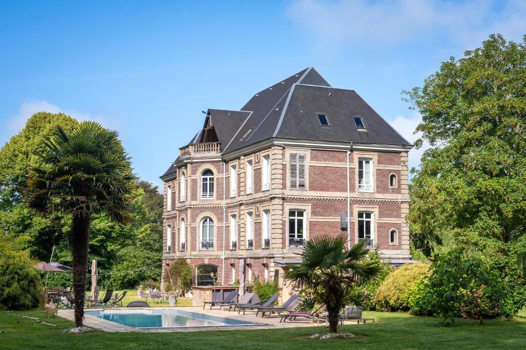 uma casa grande com uma piscina em frente em Le Petit Château de Conteville em Paluel