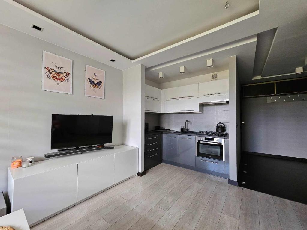 a kitchen with white cabinets and a flat screen tv at Apartament w centrum miasta z balkonem in Jastrzębie Zdrój