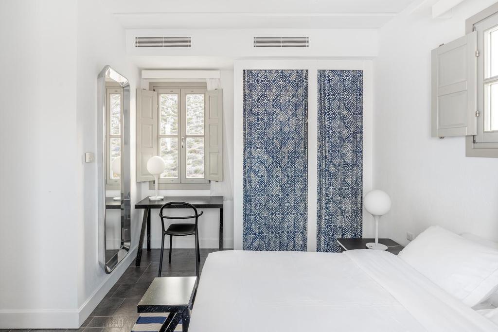 a bedroom with two beds and a desk and a table at ANEMI Folegandros in Karavostasi