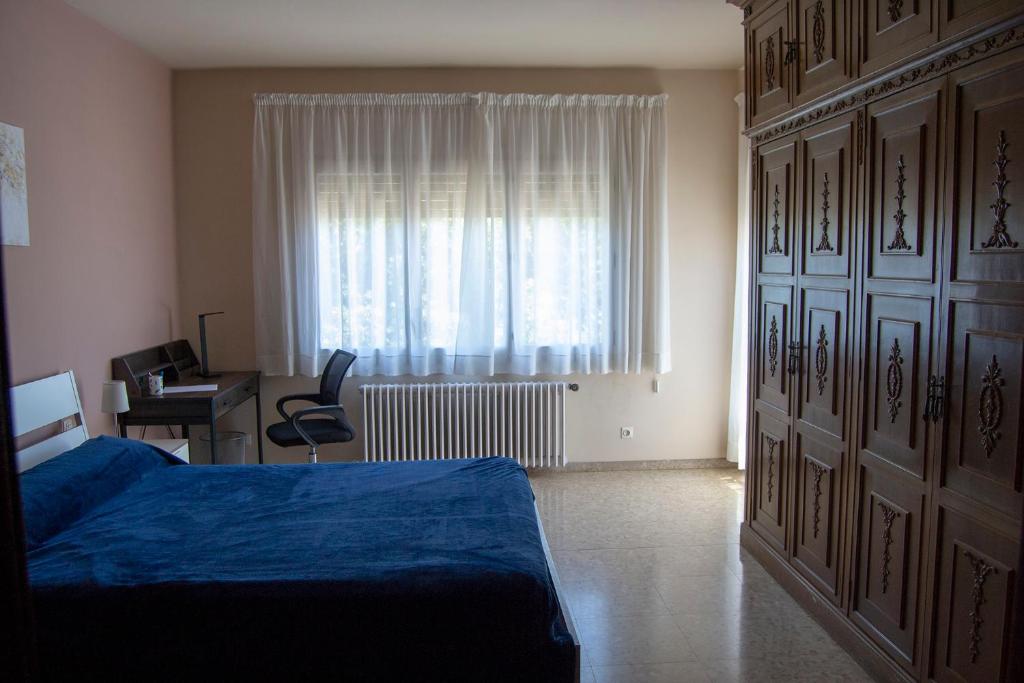 a bedroom with a bed and a desk and a window at Habitació M Cal Kim in Martorell