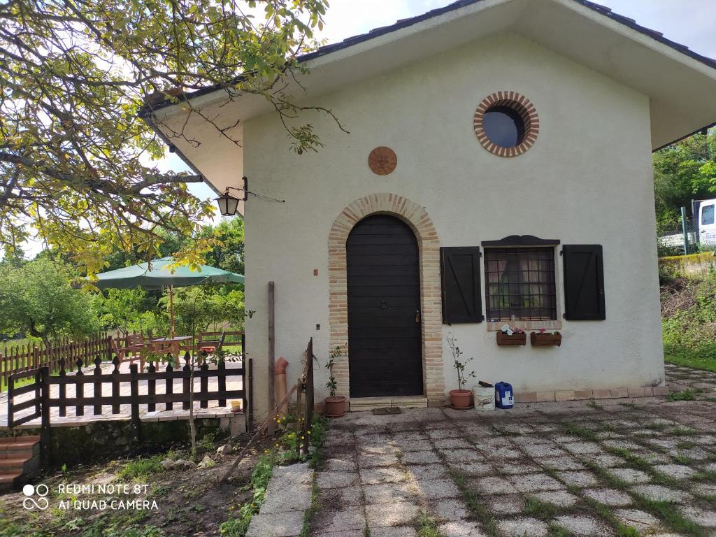 a small house with a black door and a fence at b&b chalet la vigna intera struttura in Scurcola Marsicana